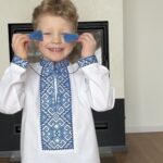 Хлопчик грається з китицями на вишиванці Блакитний оберіг